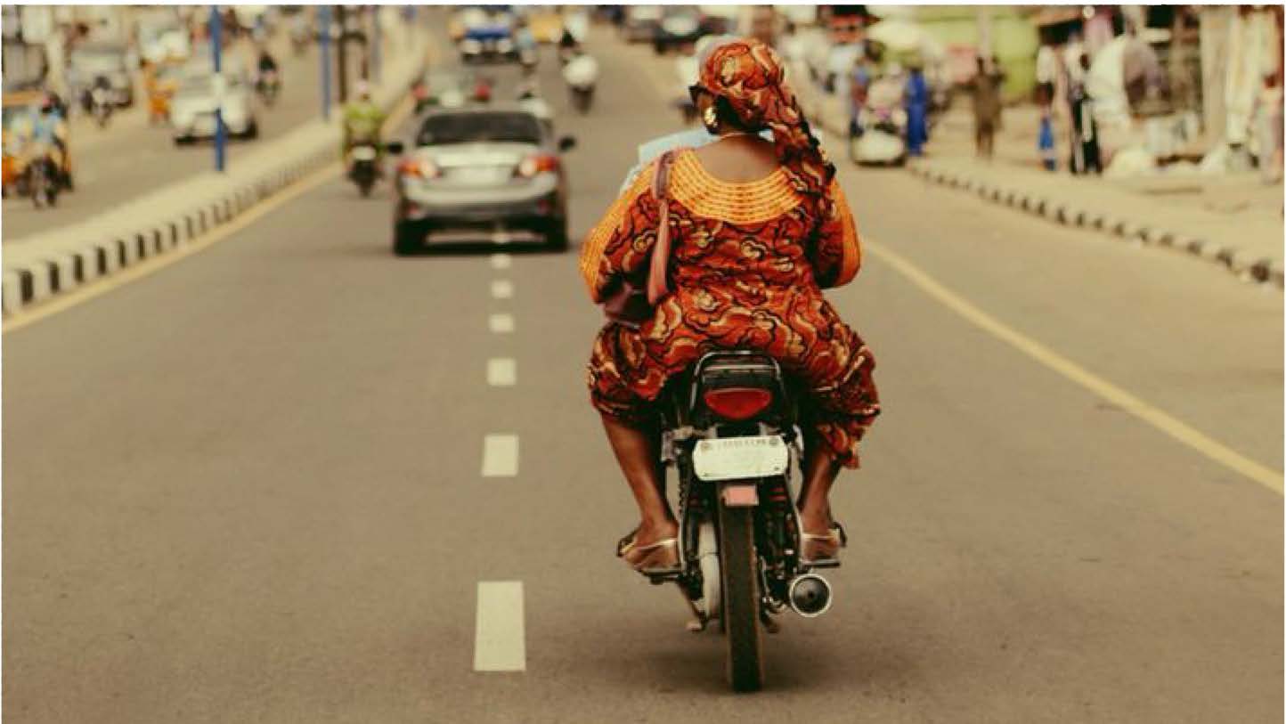 Woman on motorcycle riding through Accra